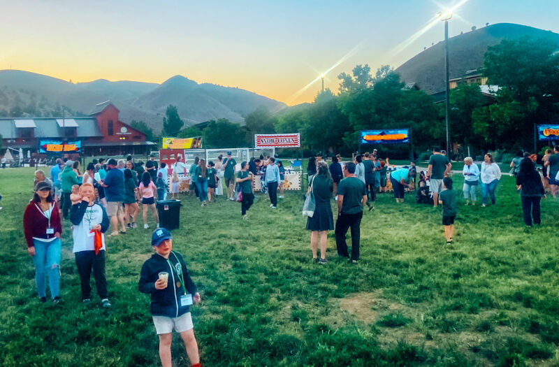 A crowd of people in a grass field at flok Family Camp West in 2023.